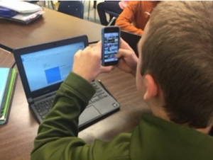 Searching photos on a phone while writing on a Chromebook.